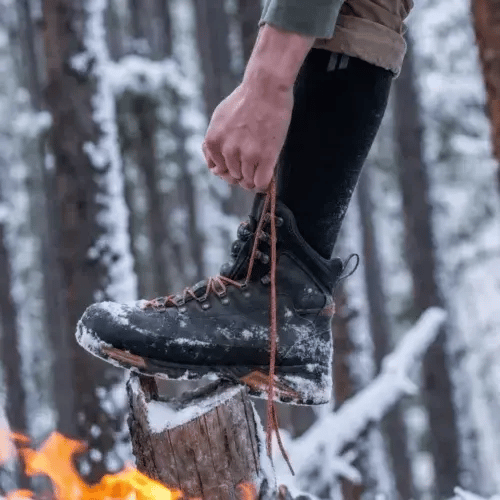 Guy tieing his boots outdoors showing off our Boot Socks
