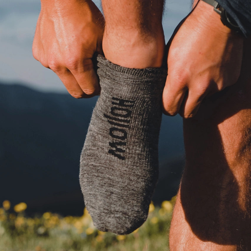 Person pulling up grey Hollow socks